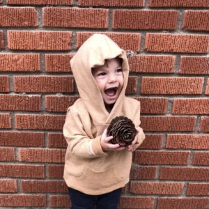 toddler boy wearing hoodie holding pinecone